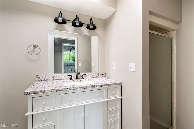 bathroom featuring a shower with shower door and vanity