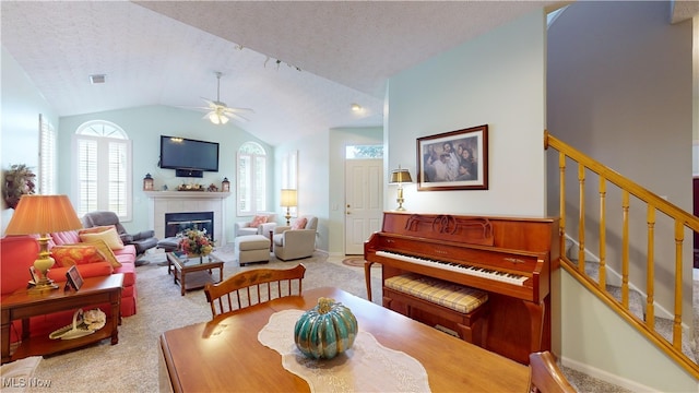 carpeted dining room with ceiling fan, a textured ceiling, a tiled fireplace, and vaulted ceiling