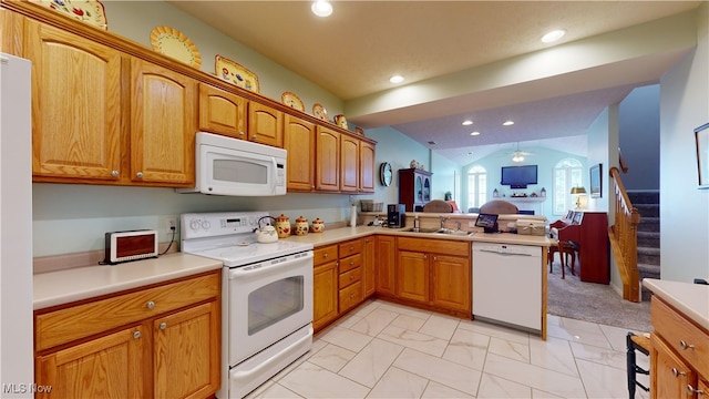 kitchen featuring white appliances, kitchen peninsula, vaulted ceiling, and sink