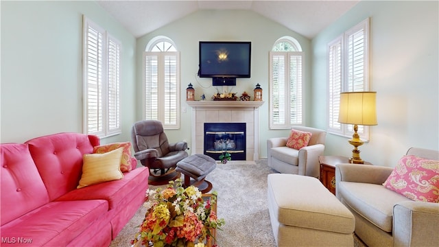 carpeted living room with a tiled fireplace, vaulted ceiling, and a healthy amount of sunlight