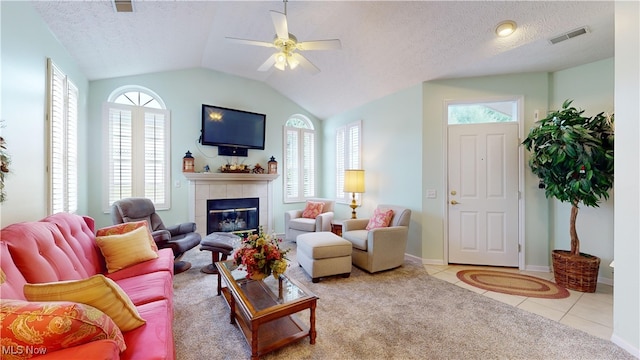 living room featuring a healthy amount of sunlight, vaulted ceiling, a tiled fireplace, and ceiling fan