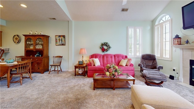 carpeted living room featuring a textured ceiling and a tiled fireplace