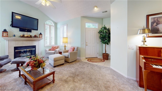 living room with a fireplace, a textured ceiling, lofted ceiling, ceiling fan, and light colored carpet