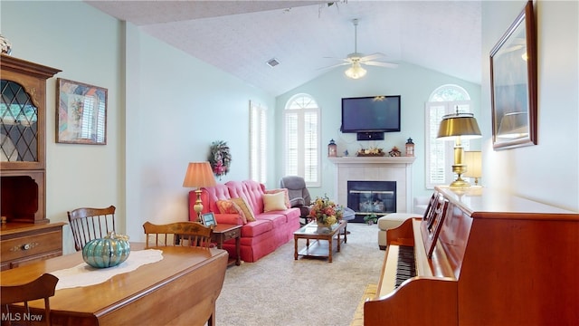 carpeted living room featuring lofted ceiling, ceiling fan, and a tile fireplace