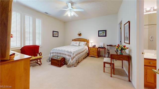 carpeted bedroom with ensuite bath, ceiling fan, and a textured ceiling