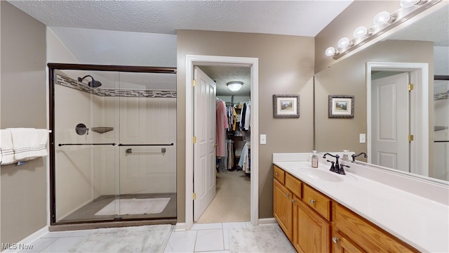 bathroom featuring a textured ceiling, tile patterned flooring, vanity, and a shower with door