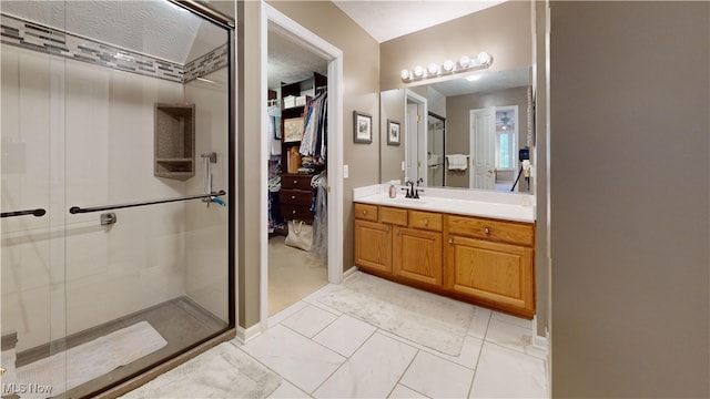 bathroom with a textured ceiling, a shower with door, and vanity