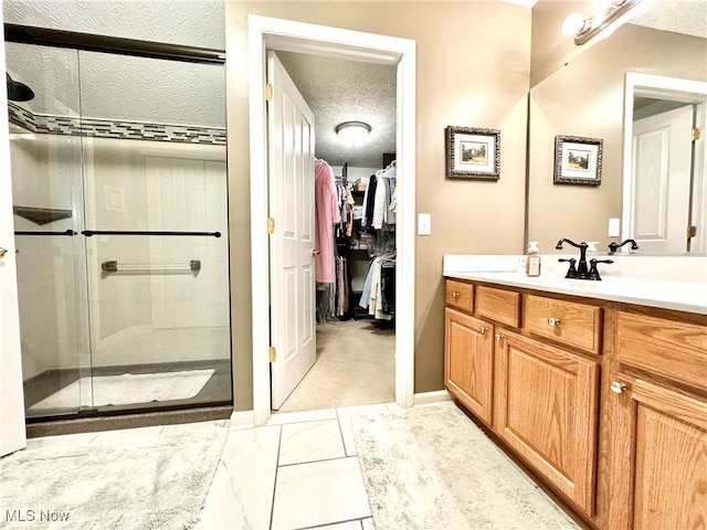 bathroom featuring a textured ceiling, an enclosed shower, and vanity