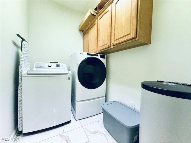 clothes washing area with separate washer and dryer and cabinets