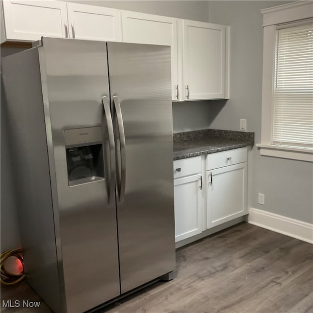 kitchen featuring wood-type flooring, stainless steel refrigerator with ice dispenser, and white cabinetry