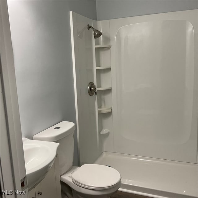 bathroom featuring vanity, a shower, and toilet