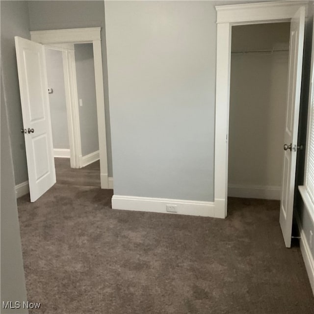 unfurnished bedroom featuring dark carpet and a closet