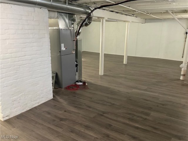 basement featuring heating unit and dark wood-type flooring