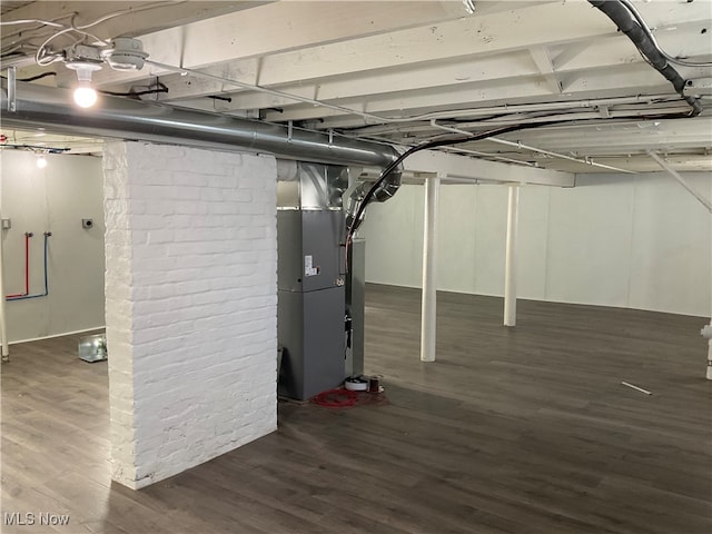 basement featuring heating unit and dark hardwood / wood-style flooring