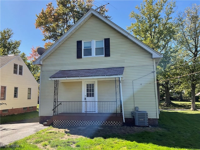 view of front of home featuring a porch, a front lawn, and central AC