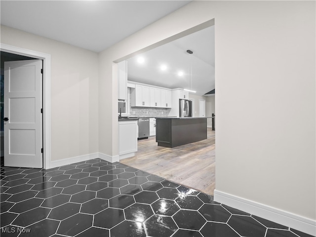 kitchen with a center island, dark hardwood / wood-style floors, backsplash, white cabinets, and appliances with stainless steel finishes