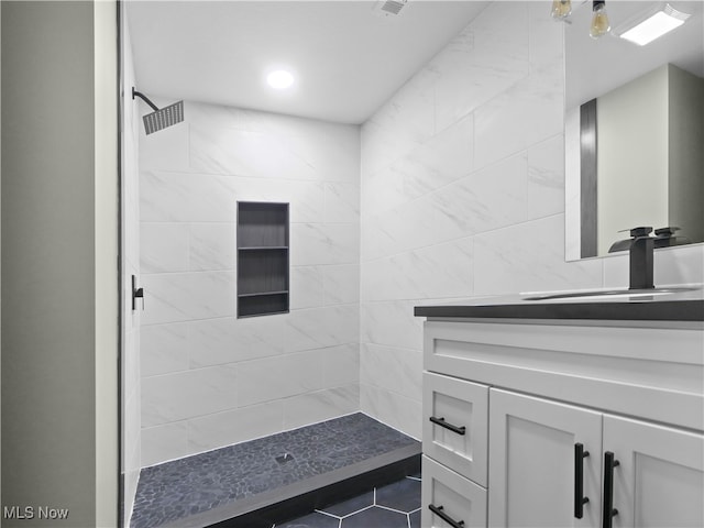 bathroom with vanity and a tile shower