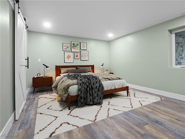 bedroom with a barn door and hardwood / wood-style flooring