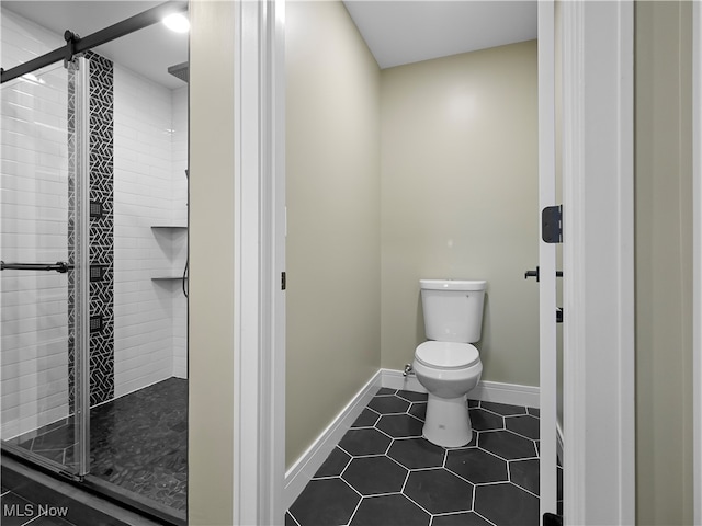 bathroom featuring tile patterned flooring, an enclosed shower, and toilet