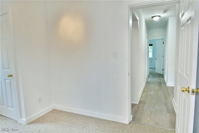 hallway with a textured ceiling and hardwood / wood-style floors