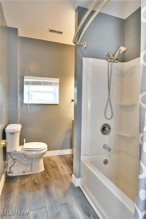 bathroom featuring shower / bath combination with curtain, hardwood / wood-style floors, and toilet