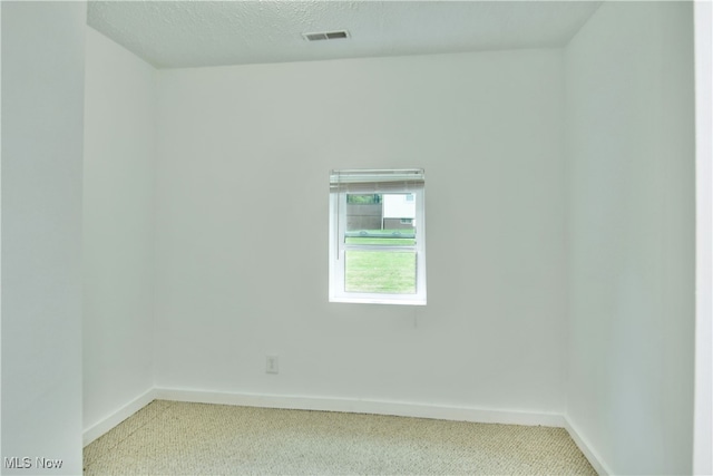 spare room featuring carpet floors and a textured ceiling