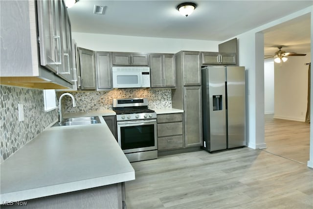 kitchen featuring light hardwood / wood-style floors, sink, stainless steel appliances, backsplash, and ceiling fan