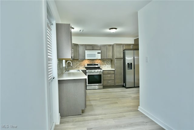 kitchen featuring appliances with stainless steel finishes, decorative backsplash, light hardwood / wood-style floors, and sink