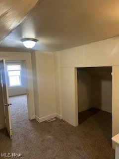 interior space featuring lofted ceiling and dark colored carpet