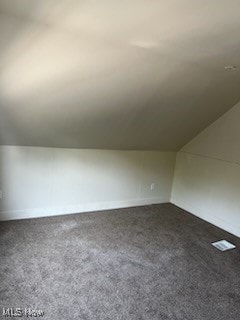 bonus room with lofted ceiling and dark colored carpet