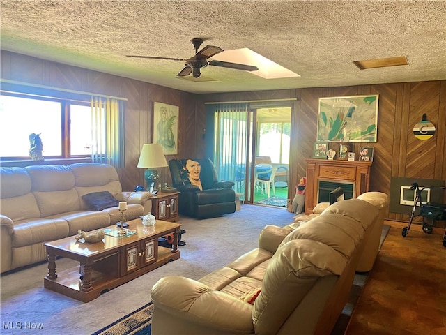 carpeted living room featuring a textured ceiling, ceiling fan, and wood walls