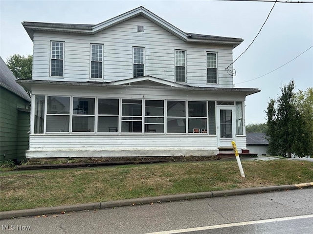 view of front of property featuring a front yard and a sunroom