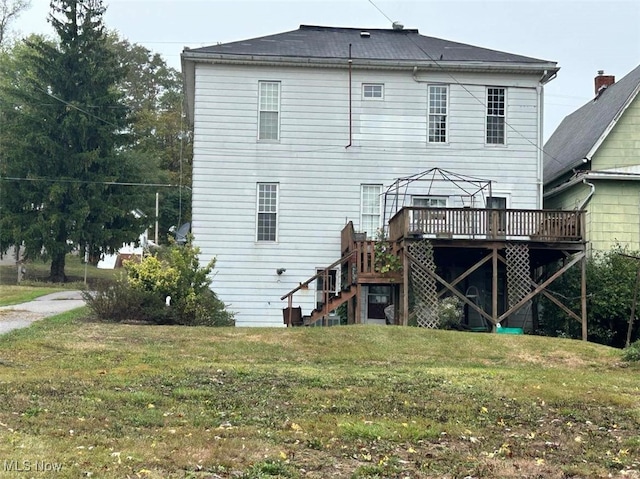 rear view of property featuring a yard and a deck