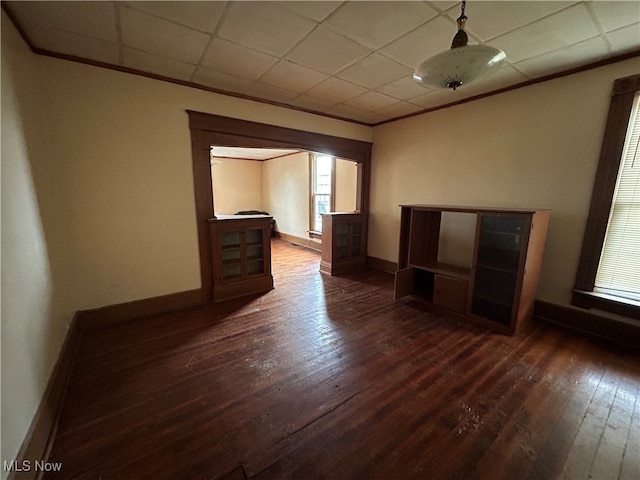 unfurnished living room featuring a drop ceiling and dark hardwood / wood-style floors