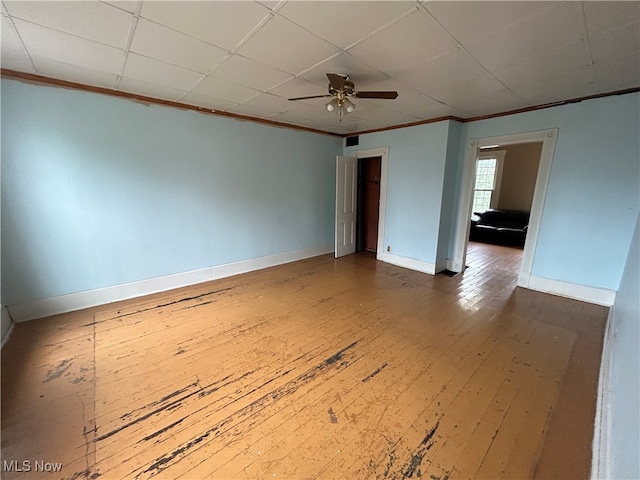 empty room with ornamental molding, wood-type flooring, ceiling fan, and a paneled ceiling