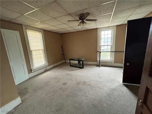 interior space with a paneled ceiling, carpet flooring, and ceiling fan