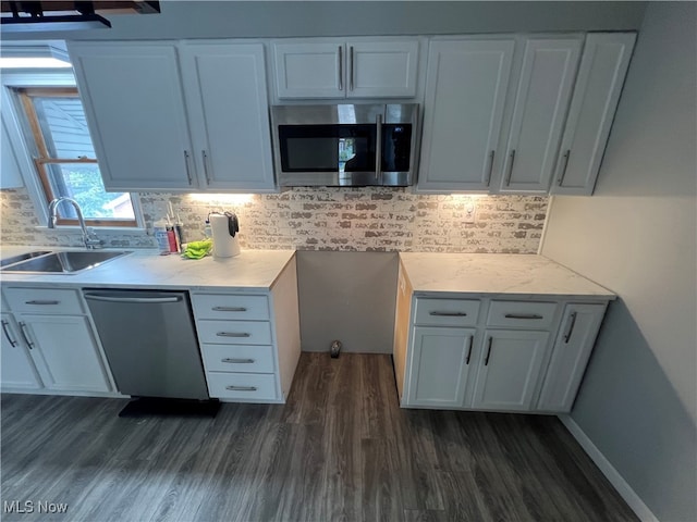 kitchen with appliances with stainless steel finishes, backsplash, sink, and white cabinetry