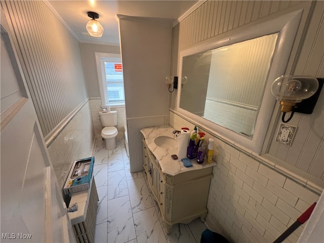 bathroom featuring tile walls, crown molding, vanity, and toilet