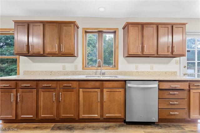 kitchen with light stone countertops, dishwasher, hardwood / wood-style floors, and sink