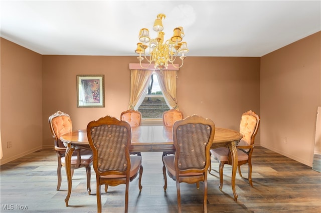 dining room with hardwood / wood-style floors and an inviting chandelier