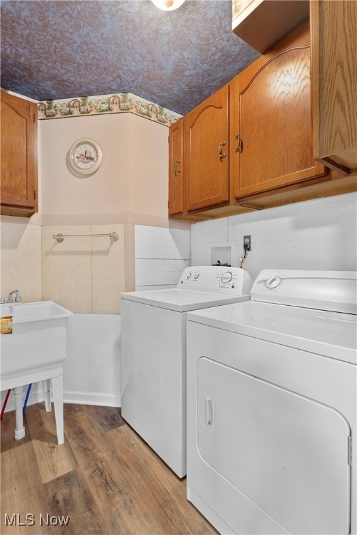 laundry room with cabinets, light wood-type flooring, and washing machine and dryer