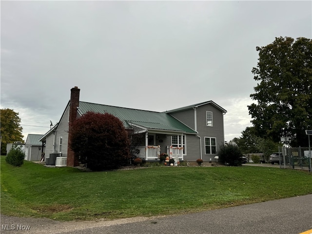 view of front of property featuring central AC unit, a front lawn, and covered porch