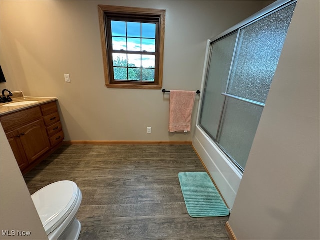 full bathroom featuring enclosed tub / shower combo, hardwood / wood-style floors, vanity, and toilet