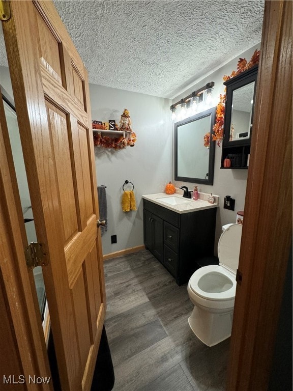 bathroom with a textured ceiling, hardwood / wood-style flooring, vanity, and toilet