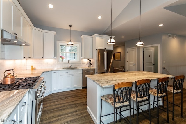 kitchen with white cabinets, high quality appliances, sink, and a kitchen bar