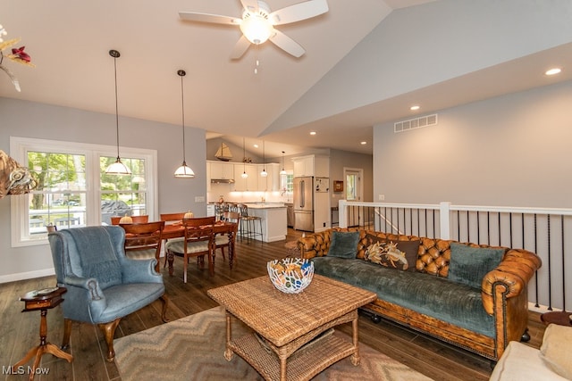 living room with dark wood-type flooring, ceiling fan, and high vaulted ceiling