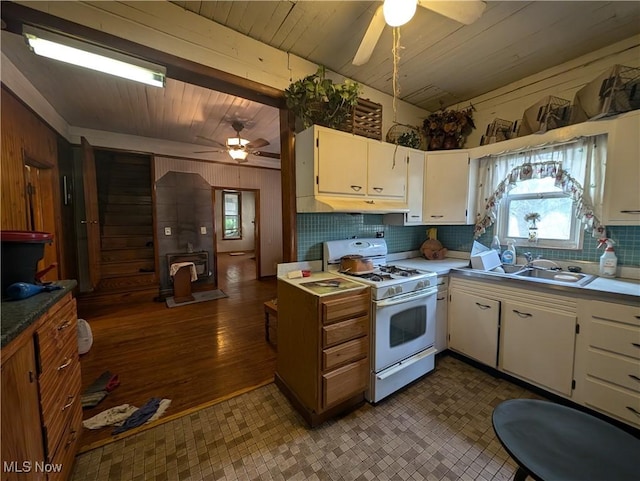 10206 Gillespie Run Rd, Petroleum, WV 26161 - kitchen featuring white gas range, ceiling fan, wooden walls, decorative backsplash, and a wood stove