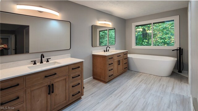 bathroom with vanity, a tub to relax in, hardwood / wood-style floors, and a textured ceiling