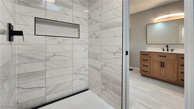 bathroom with a tile shower and vanity