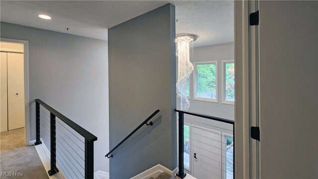 stairs featuring a textured ceiling and carpet flooring